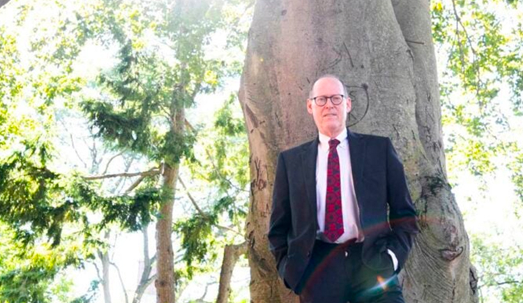 Paul Farmer standing in a suit in front of a huge tree