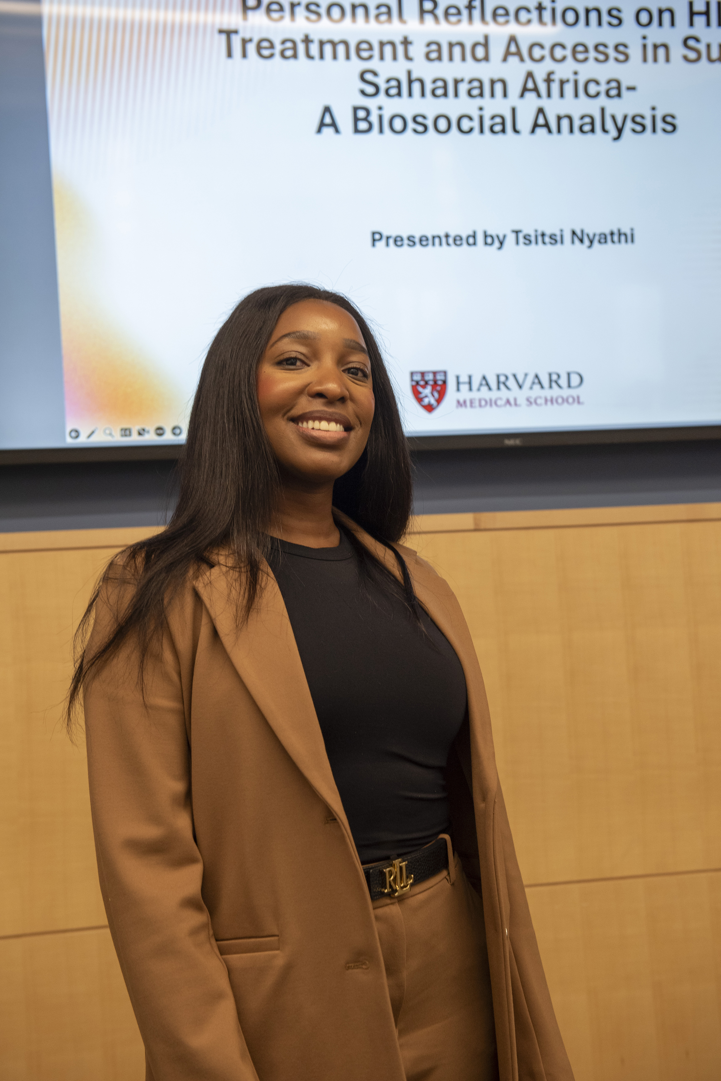 Tsitsi Nyathi stands in front of the cover slide for her capstone presentation