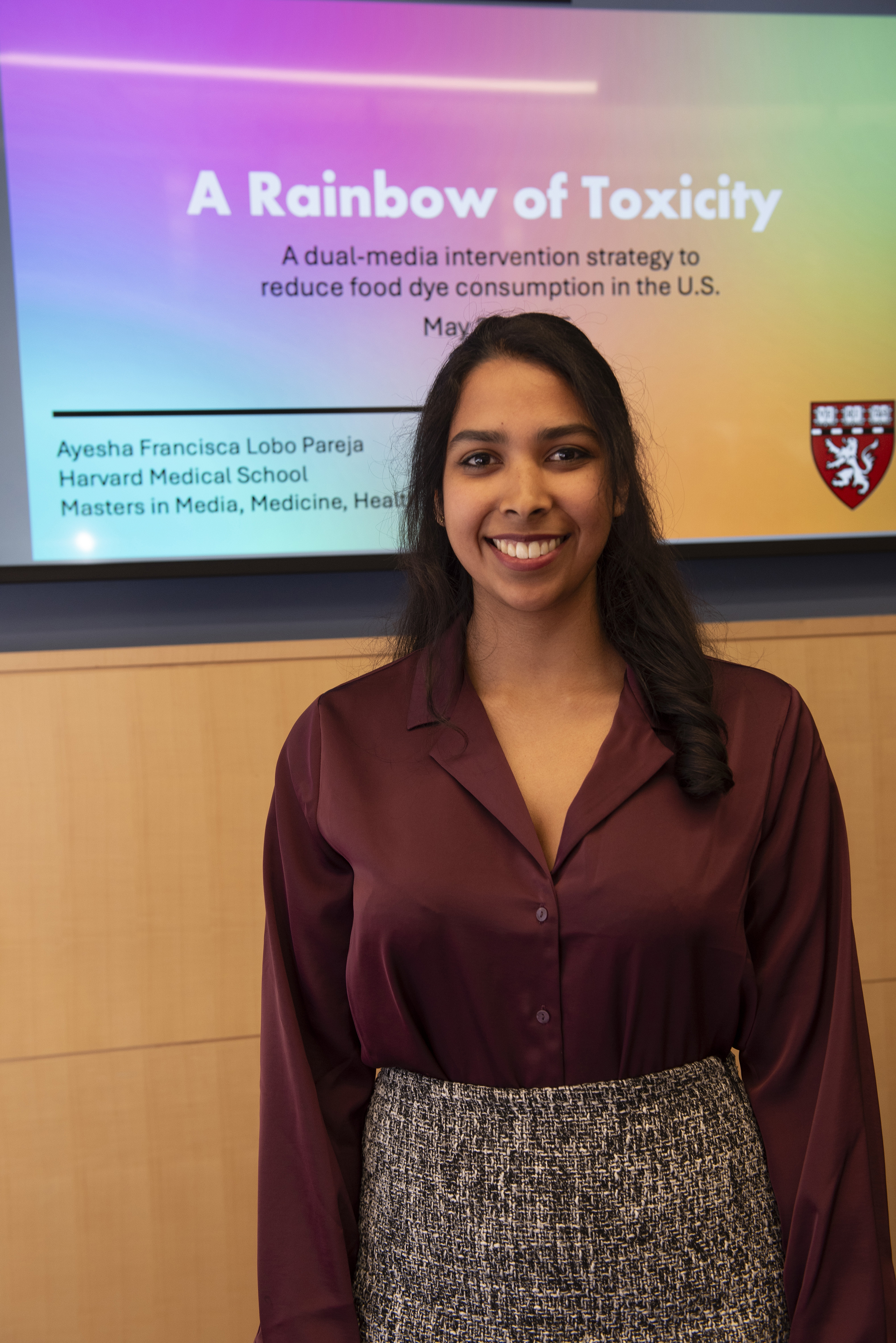 Ayesha Lobo stands in front of the cover slide for her capstone presentation