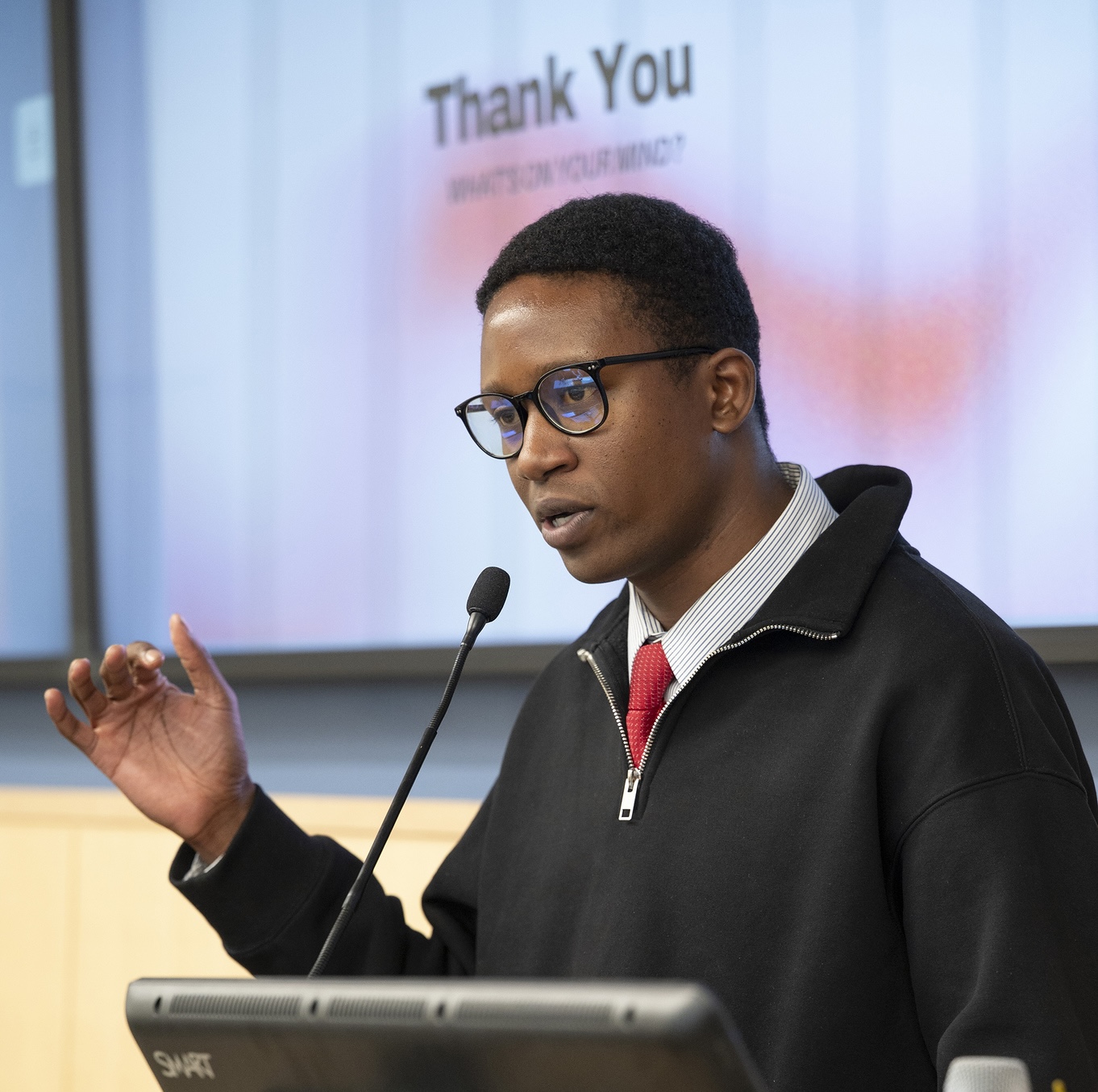 Joshua Etsimaje speaks on the podium