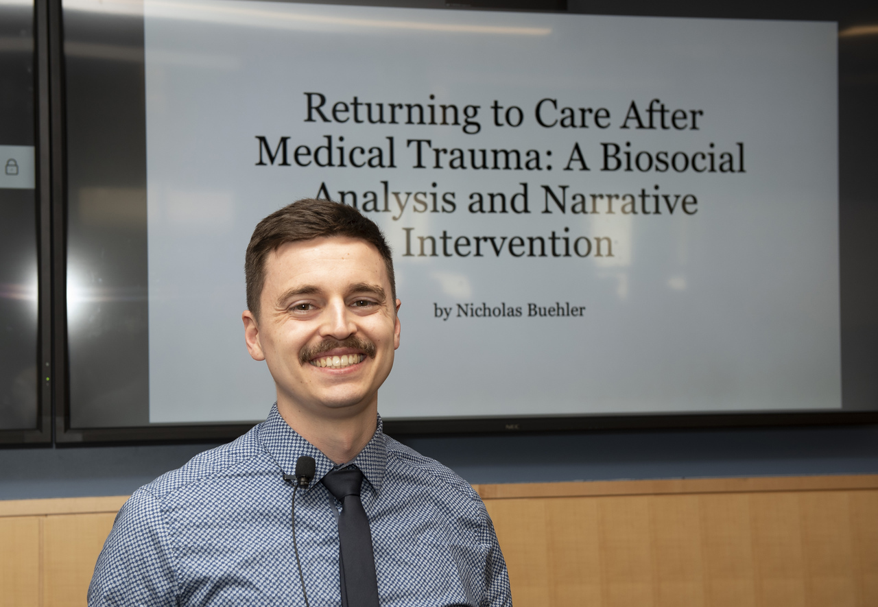 Nicholas Buehler stands in front of the cover slide for their capstone presentation