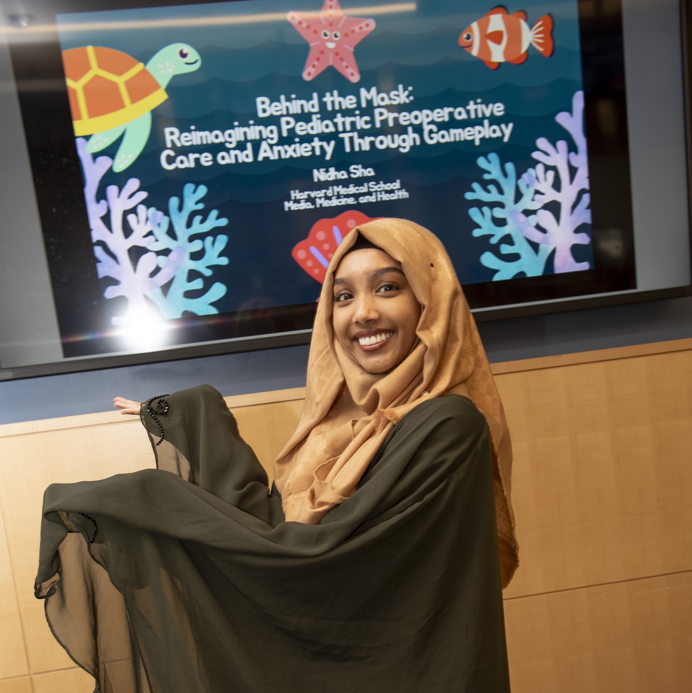 Nidha Sha poses in front of the cover slide for her capstone presentation