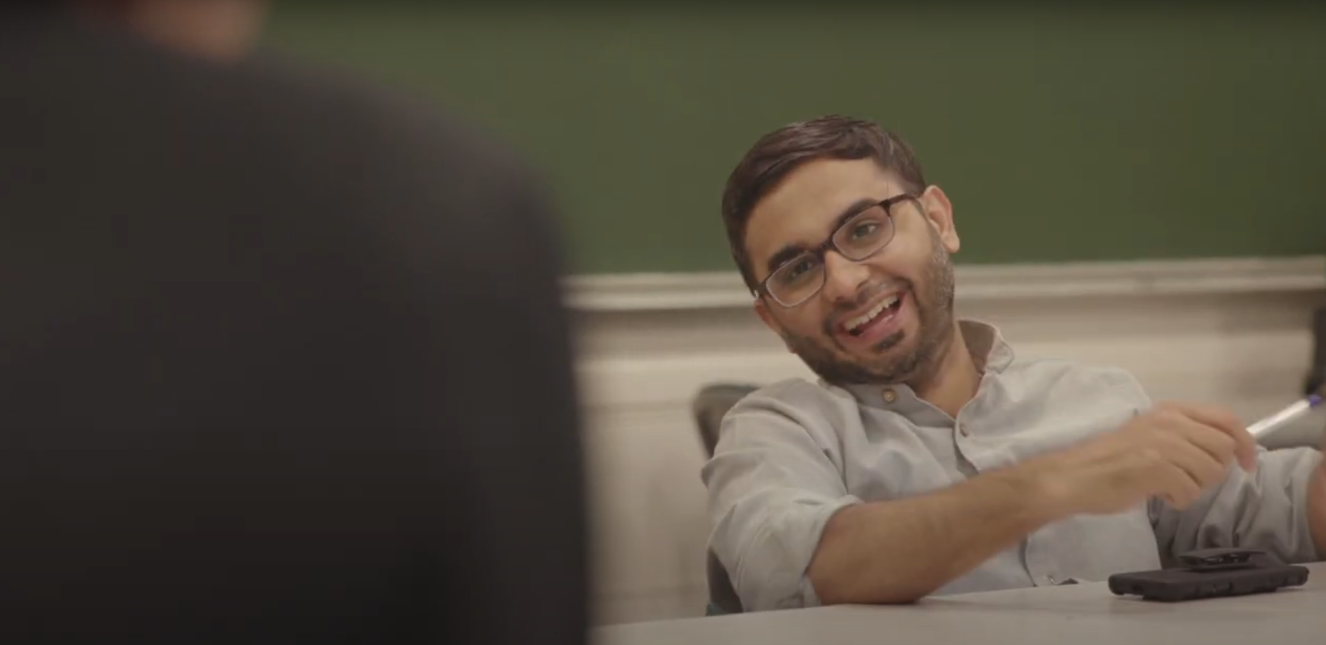 man in glasses and button down shirt laughs at camera