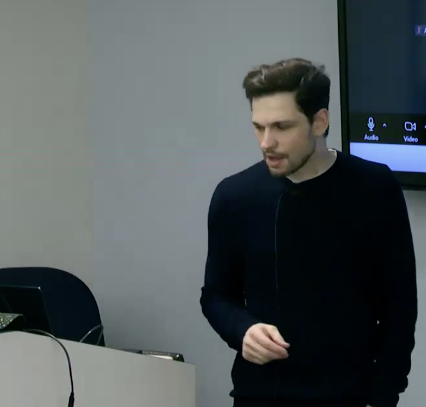 Jason Silverstein wearing a black sweater, standing in front of a podium, teaching a class
