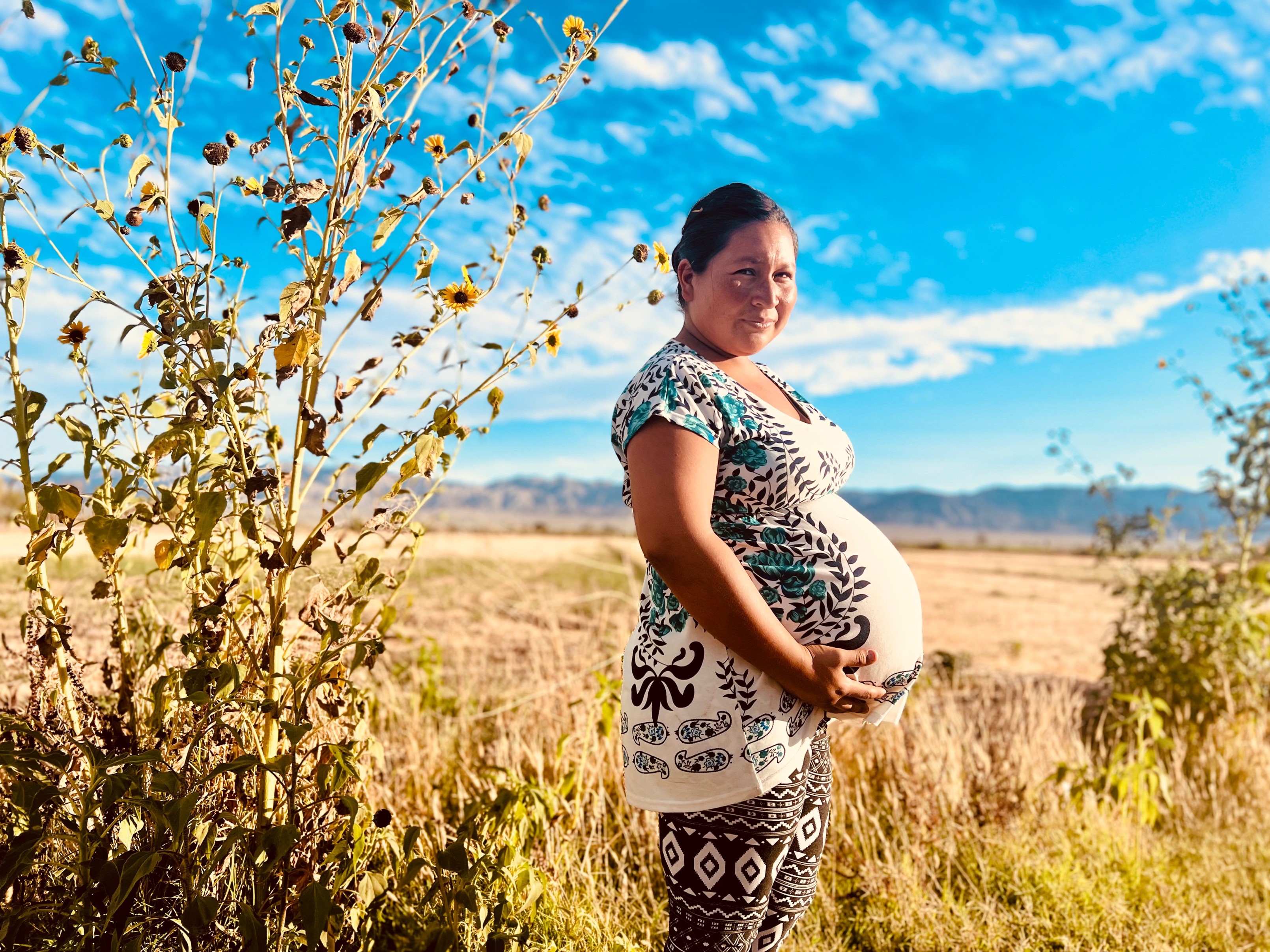 Pregnant woman in field of weeds and flowers
