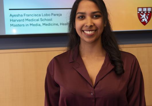 Ayesha Lobo stands in front of the cover slide for her capstone presentation