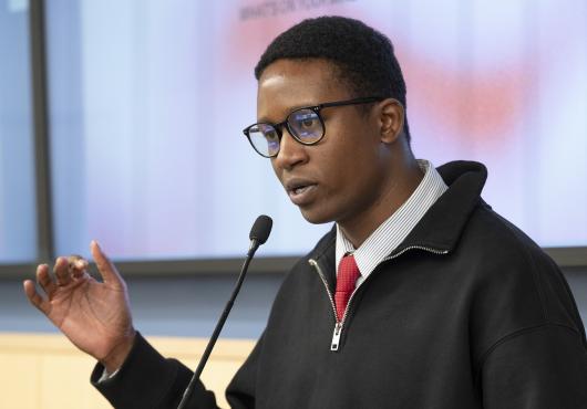 Joshua Etsimaje speaks on the podium