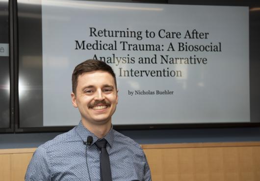 Nicholas Buehler stands in front of the cover slide for their capstone presentation