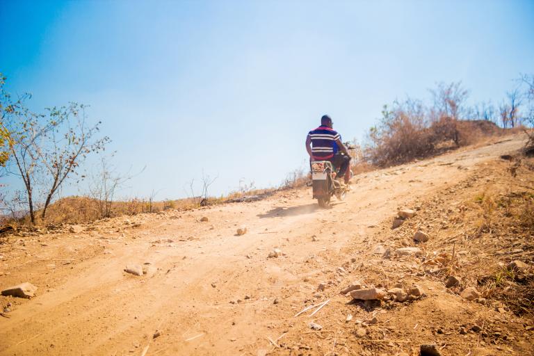 Person rides a motorbike up a dirt road