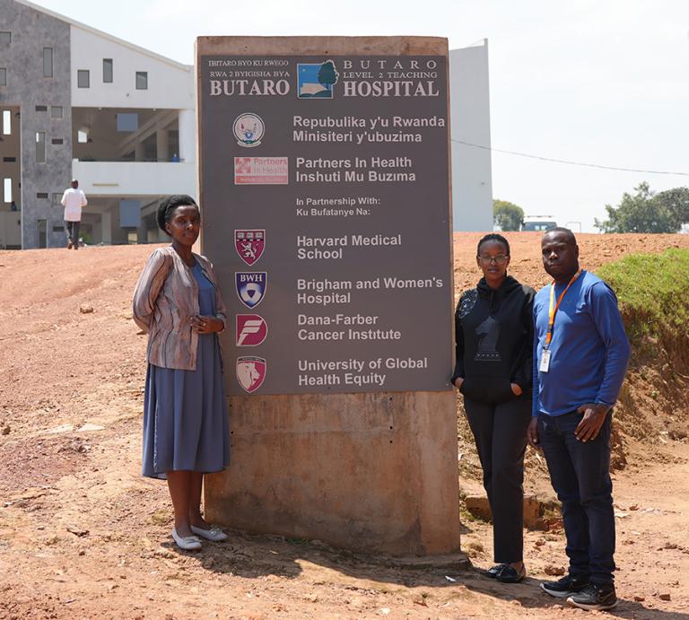 Three people stand next to a sign