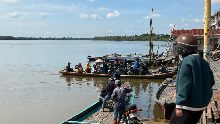 People load onto a boat to cross the Sambas river