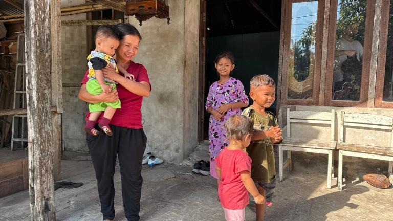 A mother, child and three children outside their door