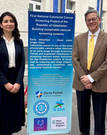 Two people stand next to a banner